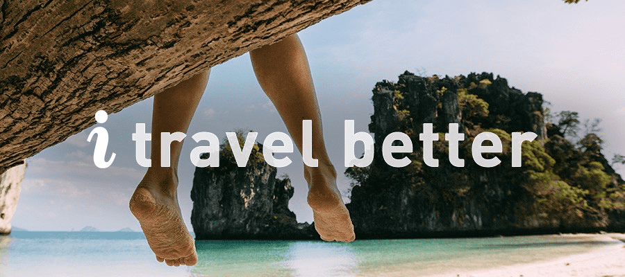 A person's leg dangle from a branch at the beach, text overlay reads "i travel better"